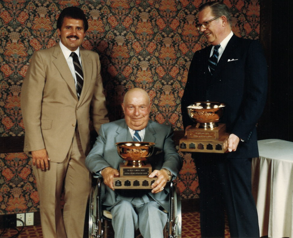 Dave Westlake at an awards presentation with colleagues and trophies