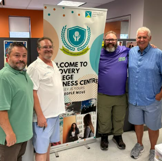 Dave Westlake with candidates and CMHA Durham staff beside the Welcome to Recovery College Wellness Centre banner